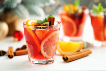 Tasty punch drink in glasses, spices and Christmas decor on white table, closeup. Space for text
