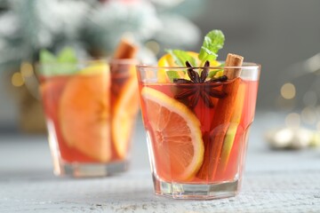 Tasty punch drink in glasses on white wooden table against background with blurred lights, space for text. Bokeh effect