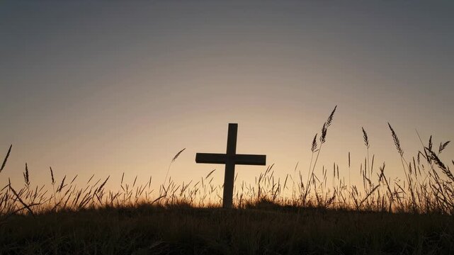 A serene video capturing a cross silhouetted against a sunset sky, conveying peace and reflection. Shot from a low camera angle.