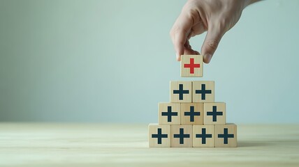 Fototapeta premium Hand stacking wooden blocks with red plus sign on top building health