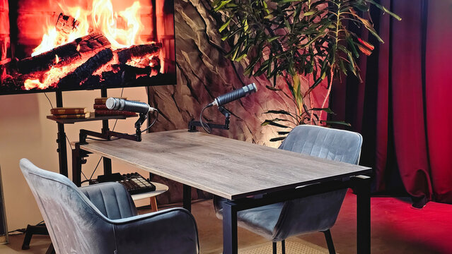A well-designed podcast studio creates a warm atmosphere with comfortable chairs and microphones set up for recording sessions. The virtual fireplace adds a cozy touch.