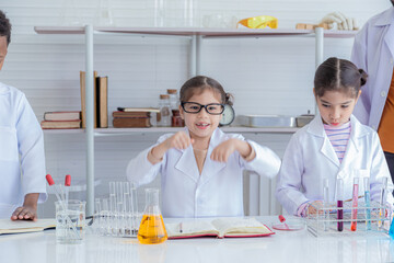 Group of multicultural African boy and elementary students girl kids friend wearing lab coat uniforms using microscope with teacher in laboratory room, lifestyle learning education in science class