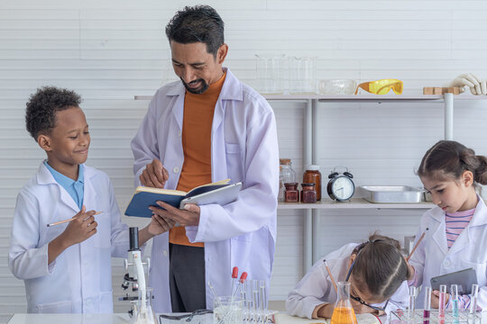Adorable Multicultural school boy and girl students kids wearing lab coats happy study with Indian teacher sending experiment paperwork in laboratory room, lifestyle learning education science class - Powered by Adobe