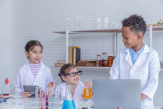 Group of multicultural African boy and elementary students girl kids friend wearing lab coat uniforms using microscope with teacher in laboratory room, lifestyle learning education in science class - Powered by Adobe
