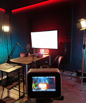  stylish audio recording studio features an on-air sign, vibrant studio lights, and neatly arranged microphones, creating an inviting atmosphere for content creation.