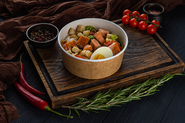 Caesar salad with salmon in disposable bowl