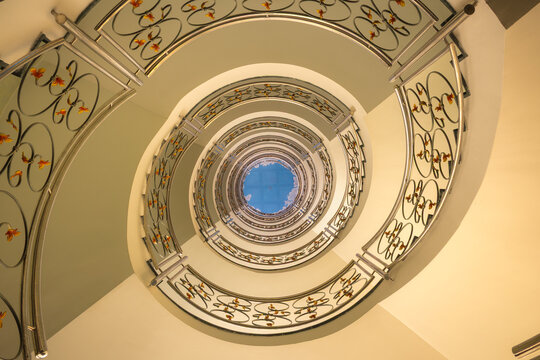 Imagen abstracta y art&iacute;stica del hueco de una escalera en forma de espiral que asciende hacia el cielo.