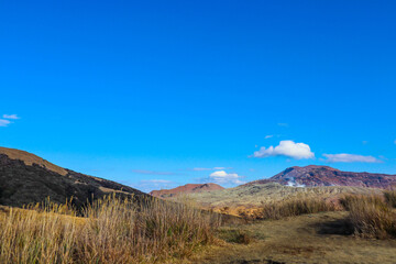 Vast Barren Plateau with Volcanic Slopes and Dry Grass under a Bright Blue Sky