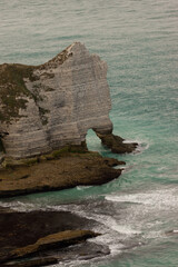 Famous white cliffs of Étretat, Normandy, France, rising above turquoise sea waters. Iconic coastal landscape known for its natural beauty and dramatic rock formations.