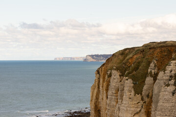 Steep white cliffs overlooking the calm sea at Étretat, Normandy. Majestic coastal landscape under a soft cloudy sky, symbolizing natural beauty and serenity.