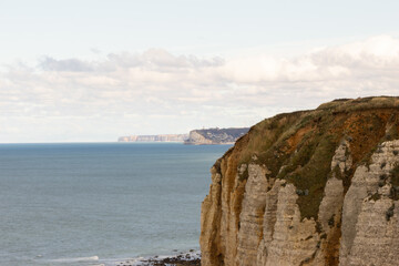 Famous white cliffs of Étretat, Normandy, France, rising above turquoise sea waters. Iconic coastal landscape known for its natural beauty and dramatic rock formations.