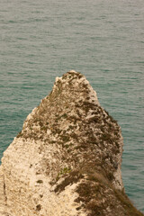 Famous white cliffs of Étretat, Normandy, France, rising above turquoise sea waters. Iconic coastal landscape known for its natural beauty and dramatic rock formations.