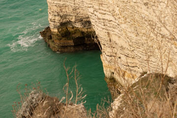 Famous white cliffs of Étretat, Normandy, France, rising above turquoise sea waters. Iconic coastal landscape known for its natural beauty and dramatic rock formations.
