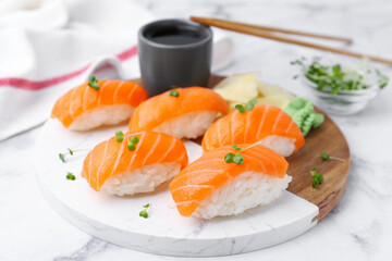 Delicious nigiri sushi with salmon, microgreens and soy sauce on white marble table, closeup