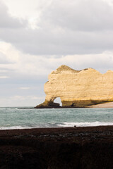 Famous white cliffs of Étretat, Normandy, France, rising above turquoise sea waters. Iconic coastal landscape known for its natural beauty and dramatic rock formations.