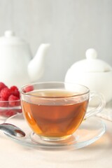 Delicious tea and raspberries on white table, closeup