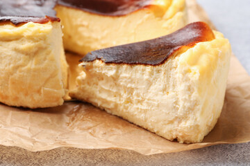 Cut Basque cheesecake on light grey textured table, closeup