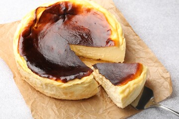 Taking piece of tasty Basque cheesecake from light grey textured table, closeup