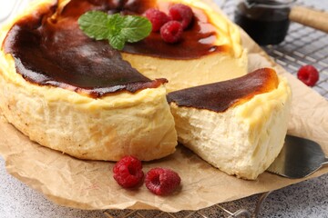 Tasty Basque cheesecake with raspberries and mint on light grey textured table, closeup