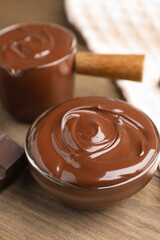 Melted chocolate and piece on wooden table, closeup