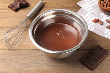 Melted chocolate, beans and pieces on wooden table