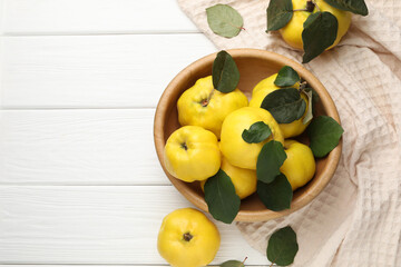 Fresh ripe quinces with leaves on white wooden table, flat lay. Space for text