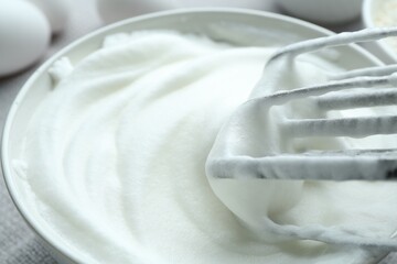 Whipped whites in bowl and mixer on table, closeup