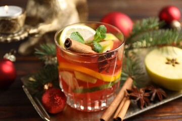 Tasty punch drink, spices and Christmas decor on wooden table, closeup