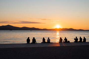 A view of the embankment in Zadar, Croatia, at sunset with silhouettes of tourists