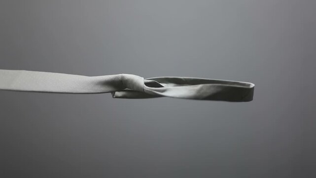 A noose hangs from a tie against a gray background. Concept of business failure. Vertical looping video.