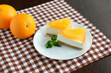 Delicious Orange Cheesecake Slices with Fresh Oranges on a Checkered Tablecloth