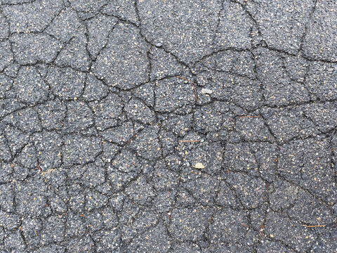 Close-up of cracked asphalt surface, showing texture and damage details