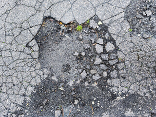 Close-up of cracked asphalt with potholes and signs of wear and tear