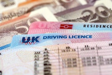 United Kingdom driving license with residence permit card on UK money close up