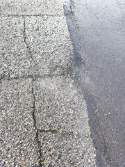 Wet asphalt and cracked pavement texture after a rain shower