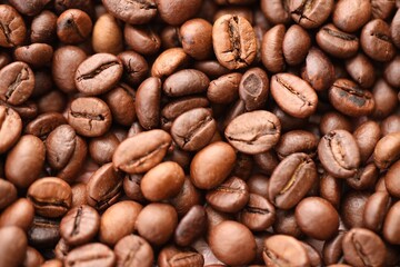 Big pile of fresh roasted brown coffee beans as flat background photo image with visible details close up