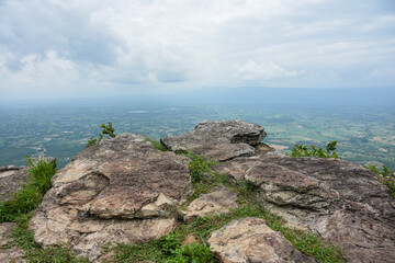Steep rocky cliff overlooks a vast green forested valley below.