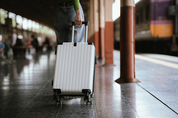 Traveler pulling a suitcase at a train station, representing travel, journey, transportation, and...