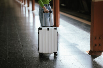 Traveler pulling a suitcase at a train station, representing travel, journey, transportation, and...