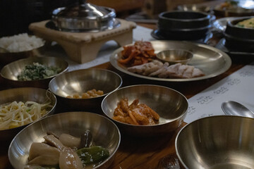 Authentic Korean Full Course Meal (Hansik Hansang) served on traditional Yugi Brassware with Banchan, Gyeran-jjim, and Main Dishes in a Rustic Dining Setting.