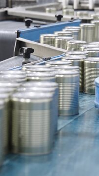 Green peas in cans on a conveyor belt in a canned food production facility