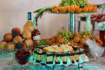 Elegant Dessert Buffet Display with Assorted Cakes, Fresh Fruits, and Beverages on Tiered Glass Stands