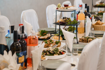 Elegant catering buffet table with gourmet appetizers, wine bottles, and tiered serving trays in a sophisticated event setting