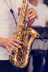 Close-up of a musician playing a golden saxophone with hands on keys during live performance