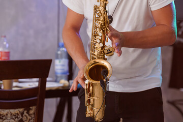Obraz premium Man playing golden saxophone in indoor setting with soft lighting and musical performance ambiance