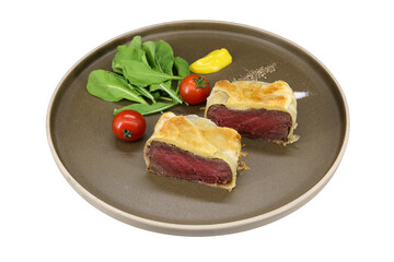 A mouthwatering view of Beef Wellington on the plate with fresh ingredients. This image showcases two perfectly cooked Beef Wellington slices, accompanied by fresh arugula.