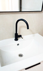 A close-up of a black faucet in a bathroom with a mirror and sink. White bathroom
