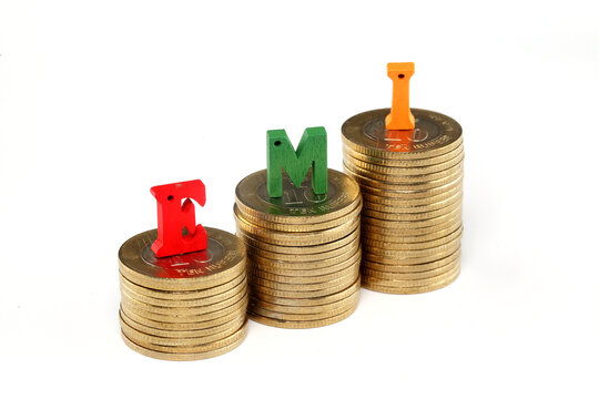 Stack of coins and Equated Monthly Installment EMI letters on white background