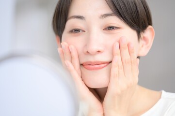 鏡を見て肌を確認する日本人女性