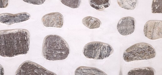 Cement white wall with huge stones and rock ornament decoration. Design detail and pattern  texture. Closeup, macro.